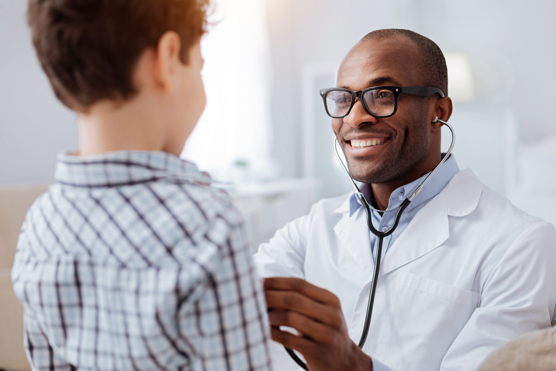 Black Male Doctor Checking Boys Heartbeat